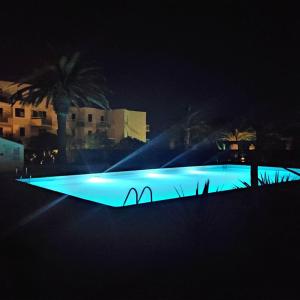 una gran piscina con luces azules por la noche en Les Capitelles : Appartement vue montagne en residence avec piscine -sur le front de mer en Saint-Cyprien