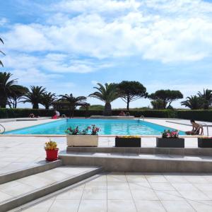 a swimming pool with stairs and palm trees at Les Capitelles : Appartement vue montagne en residence avec piscine -sur le front de mer in Saint-Cyprien