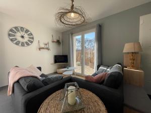 salon z kanapą i zegarem na ścianie w obiekcie Maison au calme près des plages w mieście Le Poiroux