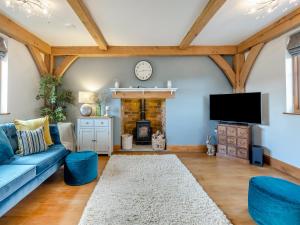 a living room with a blue couch and a fireplace at Chestnut Cottage in Leighton