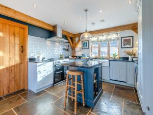 a kitchen with white appliances and a blue island at Chestnut Cottage in Leighton