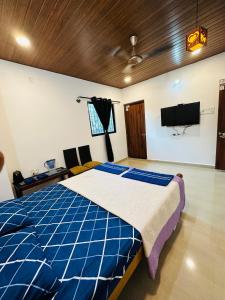 Schlafzimmer mit einem blauen und weißen Bett und einem TV in der Unterkunft St. Francis Xavier in Velha Goa