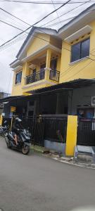una moto parcheggiata di fronte a una casa gialla di FAI Bogor Backpacker by SPAZIE a Bogor