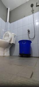 a bathroom with a toilet and a blue bucket at FAI Bogor Backpacker by SPAZIE in Bogor