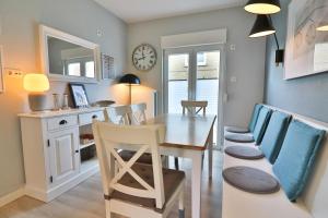 a dining room with a table and chairs and a clock at Langeooger Viermaster - Blaues Segel in Langeoog +11 photos