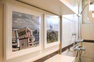 two pictures on a wall next to a sink in a bathroom at Langeooger Viermaster - Blaues Segel in Langeoog