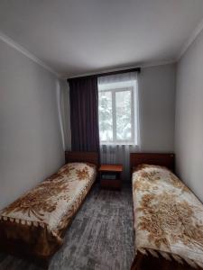 two beds in a small room with a window at University Hotel Tsakhkadzor in Tsaghkadzor