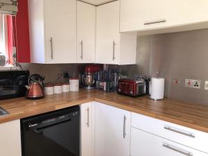 a kitchen with white cabinets and a black dishwasher at The Cottage Cox Hill Chacewater in Truro