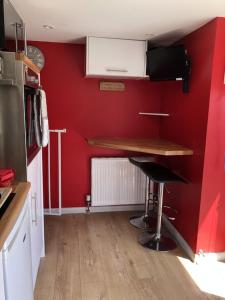 a kitchen with a red wall with a counter and a stool at The Cottage Cox Hill Chacewater in Truro