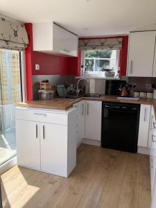 a kitchen with white cabinets and a black dishwasher at The Cottage Cox Hill Chacewater in Truro