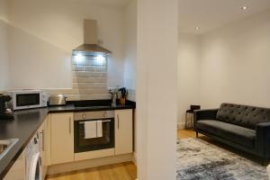a kitchen with a couch and a stove top oven at Swindon Apartments by Charles Hope in Swindon