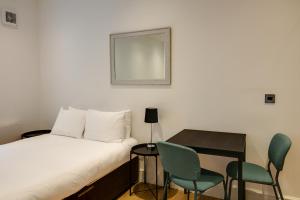 um quarto com uma cama, uma mesa e cadeiras em Swindon Apartments by Charles Hope em Swindon
