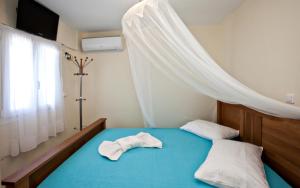 a bedroom with a blue bed with a mosquito net at Grand View Tinos in Tinos Town