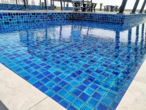 a swimming pool with blue tiles on it at FREE WIFI-FI Travelers HomestySitiawan 5-8pax The Venus Aparment in Seri Manjung