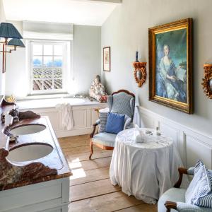 a bathroom with two sinks and a table with a chair at Château du Tertre in Arsac