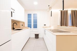 una cocina blanca con armarios blancos y fregadero en Arriaga, en Bilbao