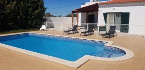 een zwembad met stoelen en een huis bij Villa Sunset Lovers in Alcantarilha