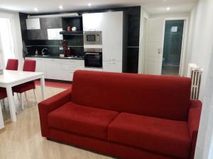 a living room with a red couch and a kitchen at A Casa di Maria 2 in Cavallino di Lecce