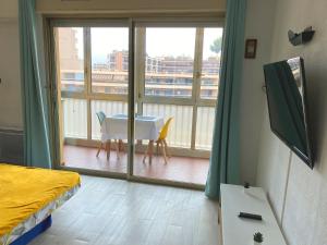 a room with a bed and a table and a balcony at Coquet logement front de mer in Cagnes-sur-Mer