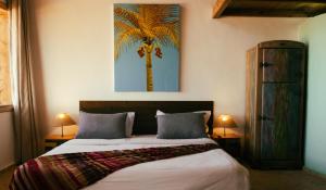 a bedroom with a bed with a palm tree painting on the wall at Westpoint Dakhla in Dakhla