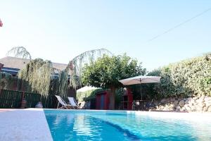una grande piscina con ombrellone e tavolo e sedie di El Cedre Blau Vivienda con piscina en Granollers a Granollers
