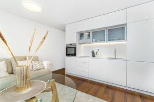 cocina y sala de estar con armarios blancos y mesa de cristal en Bombarda Apartments VII by Innkeeper, en Oporto