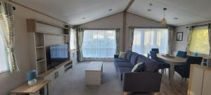 a living room with a blue couch and a tv at Luxury Lodge @ Hoburne Devon Bay in Torquay