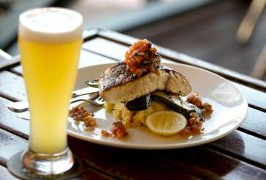 a plate of food on a table with a glass of beer at Bayside Holiday Apartments in Broome