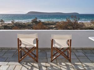 two chairs sitting on a patio overlooking the ocean at Golden Beach Villa Paros in Chrissi Akti