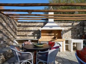 a patio with a table and chairs and a fireplace at Golden Beach Villa Paros in Chrissi Akti