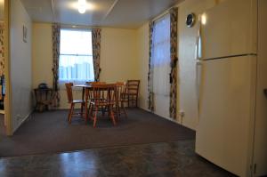 a kitchen with a table and chairs and a refrigerator at GreenGate Cottages in Strahan