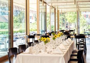 a long table with yellow flowers in a restaurant at ODELYA - Stadthotel im Park in Basel