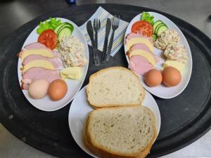 three plates of food on a black tray with eggs and bread at Agroturystyka U Siwego in Rokitki