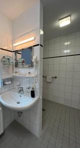 La salle de bains blanche est pourvue d'un lavabo et d'un miroir. dans l'établissement Hotel Columbus und Glamping, à Bremerhaven
