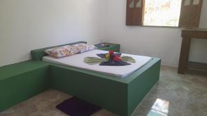 una cama verde con un juguete en una habitación en Axe Mainha Flats e Kitnet en Morro de São Paulo