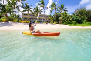 a woman sitting on a kayak in the water on a beach at Moana Sands Beachfront Hotel in Rarotonga