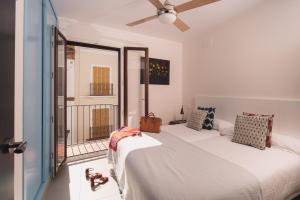 a white bedroom with a bed and a balcony at Eva Recommends San Lorenzo in Seville