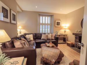 a living room with a leather couch and a fireplace at Honeywood House in Grasmere