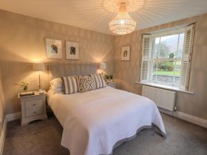 a bedroom with a bed and a window and a chandelier at Honeywood House in Grasmere
