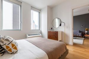 a white bedroom with a bed and a mirror at Hells Kitchen 2BR w Pool DM nr Central Park NYC-469 in New York +23 photos