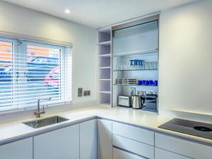 uma cozinha com armários brancos, um lavatório e uma janela em The Kinsale 4 Center em Kinsale