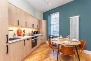 uma cozinha com mesa e cadeiras e uma cozinha com paredes azuis em Royal 2bed apartment City Center em Edinburgo