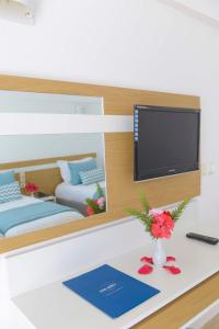a room with a tv and a table with flowers at Monarque Dar Jerba Narjess in Taguermess