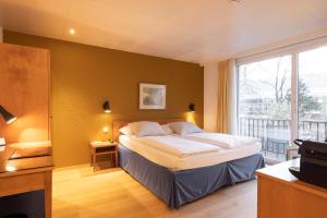 a bedroom with a bed and a large window at Engimatt City & Garden Hotel in Zurich