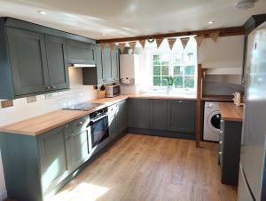 a kitchen with blue cabinets and a wooden floor at Thatchings in Bude