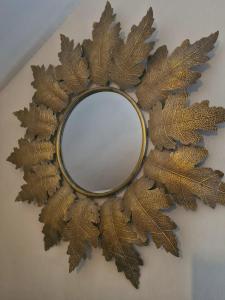 um espelho com uma coroa de folhas douradas numa parede em l'Alchimiste em Bitche