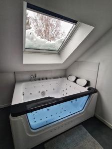 uma grande banheira num quarto com uma janela em l'Alchimiste em Bitche
