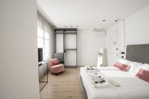 San Carlo Suite Torino في تورينو: غرفة نوم بسرير ابيض وكرسي وردي