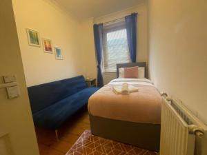 a small bedroom with a bed and a blue couch at Irongray House in Glasgow