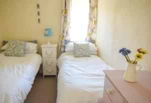 a bedroom with two beds and a vase with flowers at Water's View Cottage, Hayle in Hayle